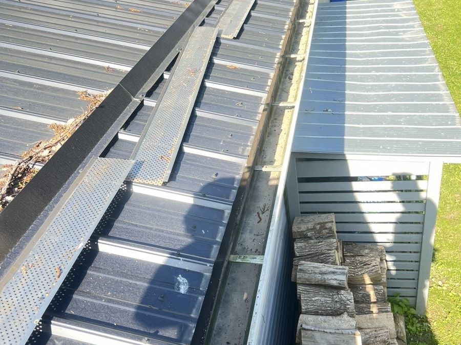 Gutter guards removed and the trough being hand-cleared during a cleaning job